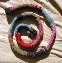 a colorful knitted shawl lying on a bed