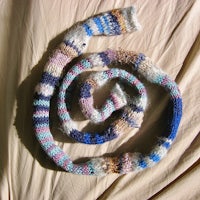 a knitted scarf laying on a bed