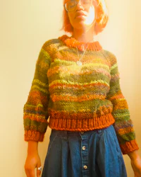 a woman wearing a striped sweater and denim skirt