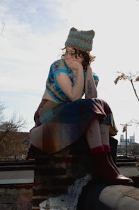 a woman sitting on top of a brick wall